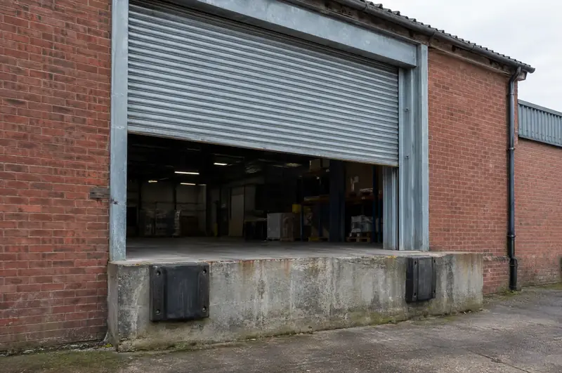 Galvanised roller shutter door raised at a raised loading dock on a brick warehouse